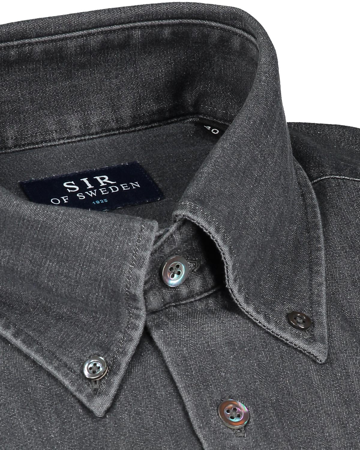 Close-up of a dark denim shirt collar with buttons and 'Sir of Sweden' label.