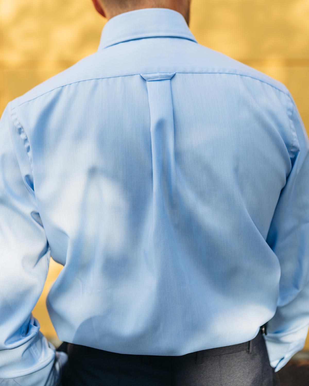Light blue dress shirt worn by a person with a blurred yellow background