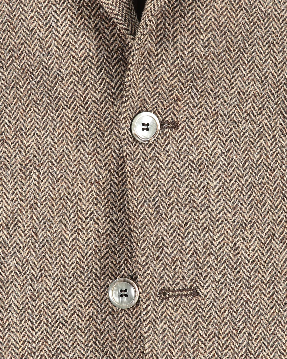 Close-up of a brown herringbone patterned jacket with buttons.