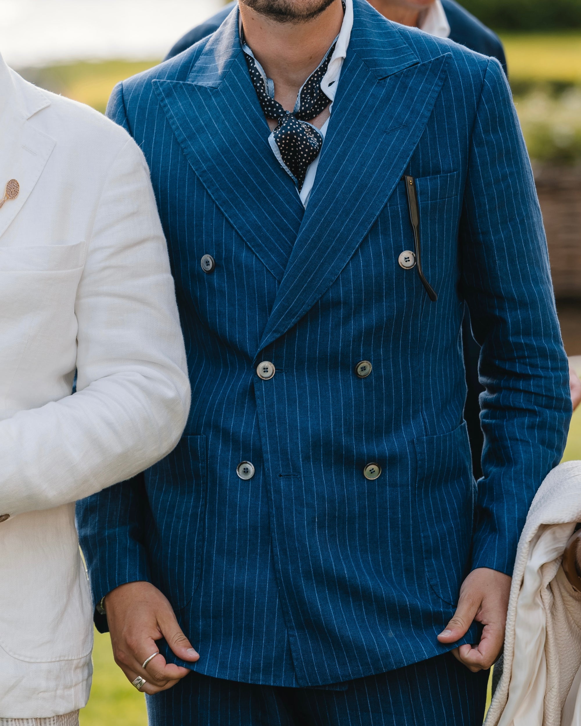 Man wearing a blue pinstripe suit with a patterned tie outdoors.