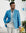 Man wearing a blue blazer and white pants standing outdoors with a blurred background
