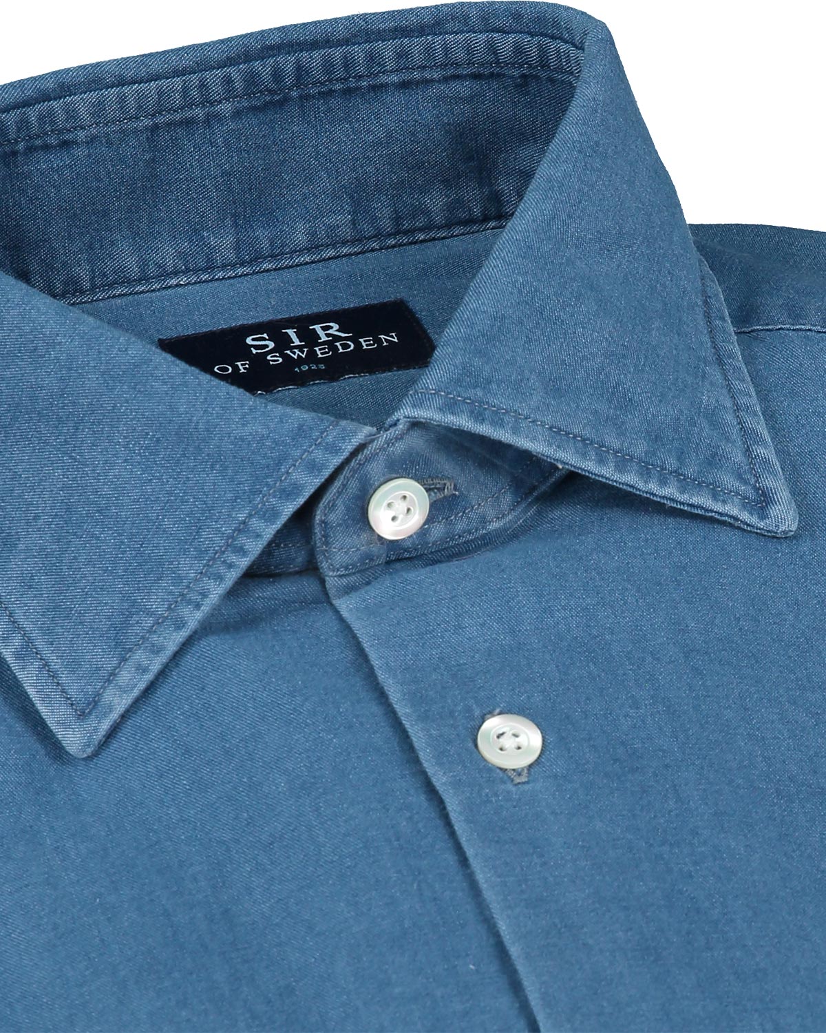 Close-up of a blue denim shirt collar with buttons and 'Sir of Sweden' label.