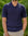 Man wearing a navy ribbed polo shirt against a green leafy background