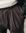 Close-up of brown pleated pants with a neutral background