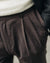 Close-up of brown pleated pants with a neutral background