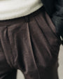 Close-up of brown pleated pants with a neutral background