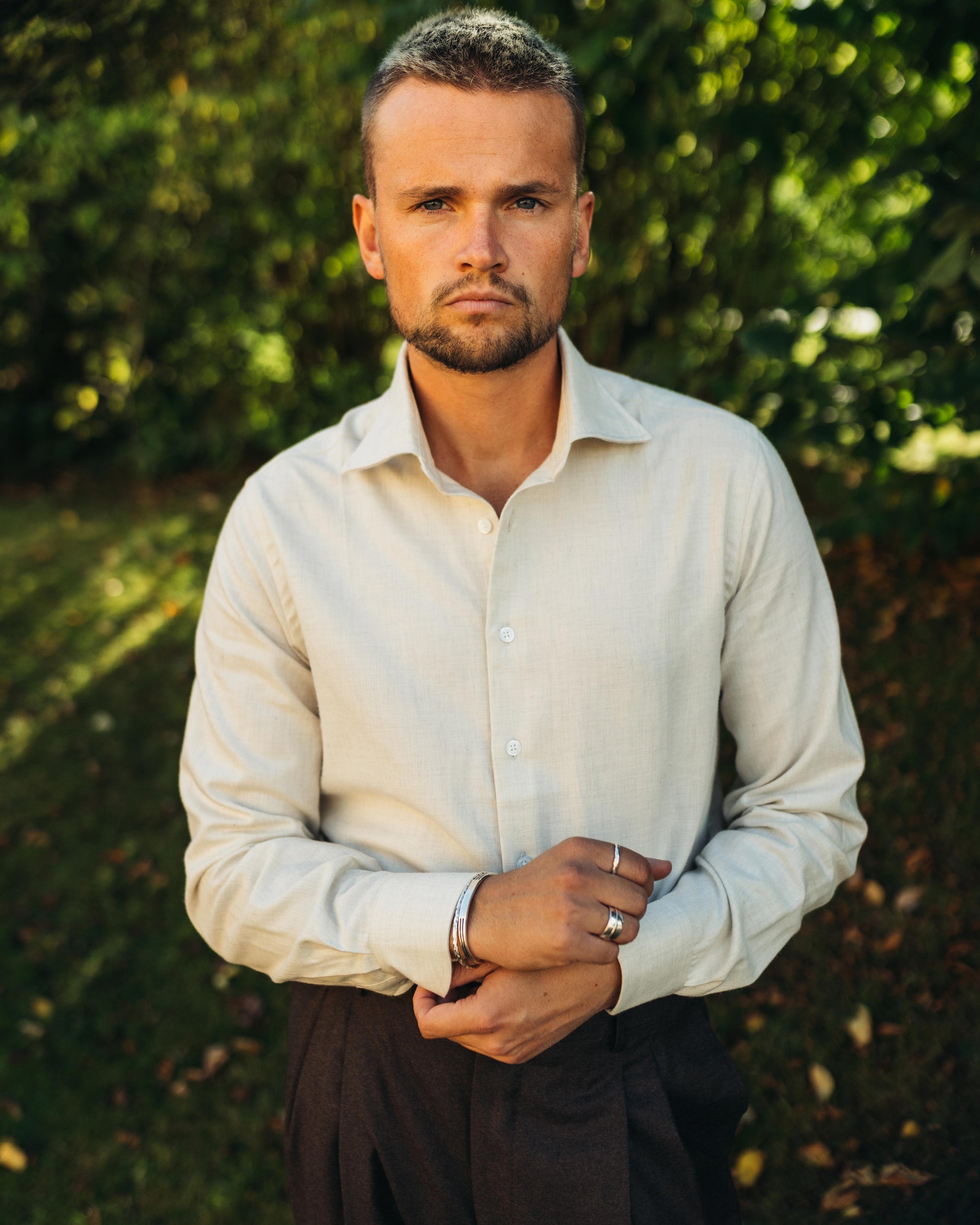 Man wearing a beige flannel shirt with a blurred green background