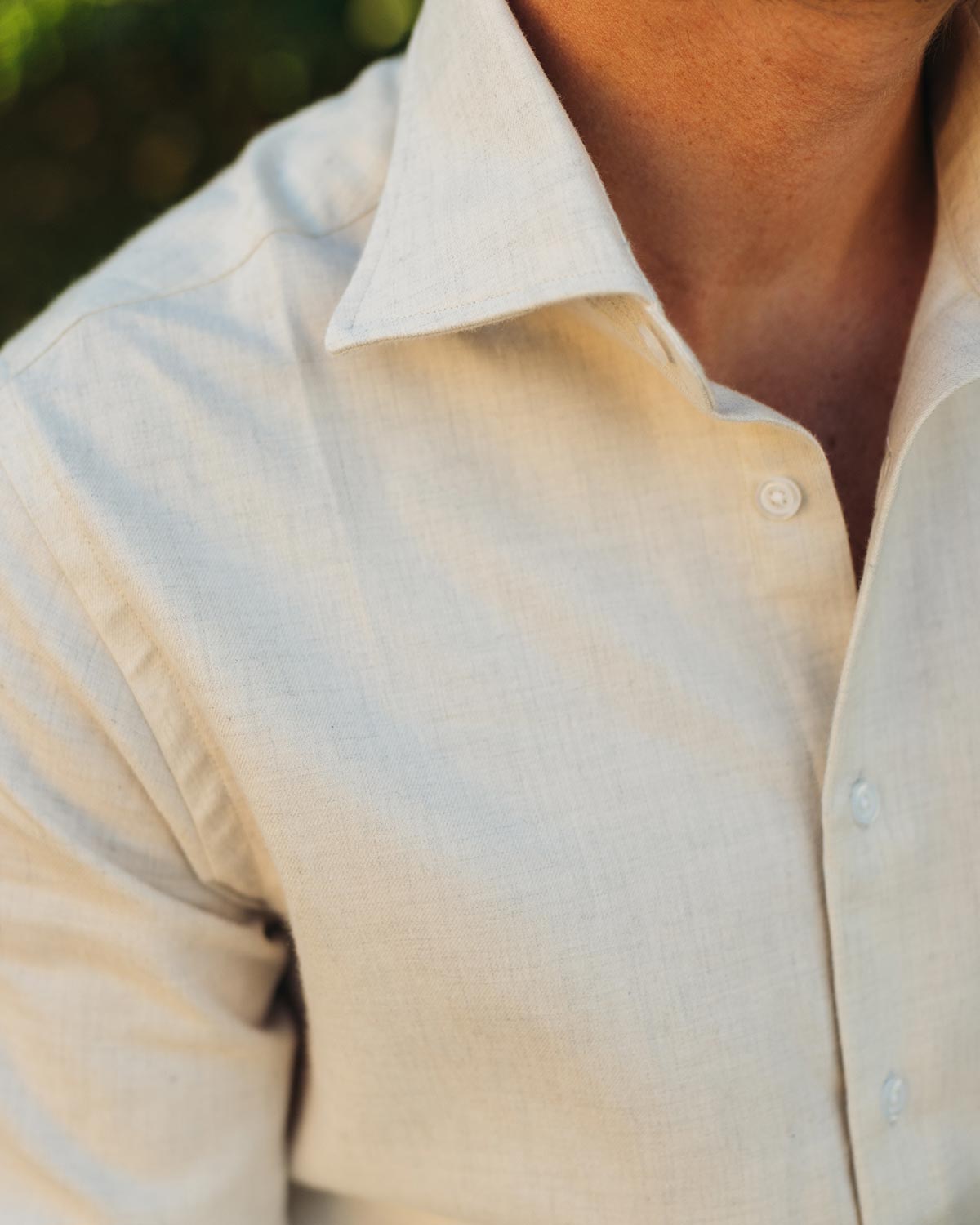 Close-up of a person wearing a beige flannel shirt with a blurred background