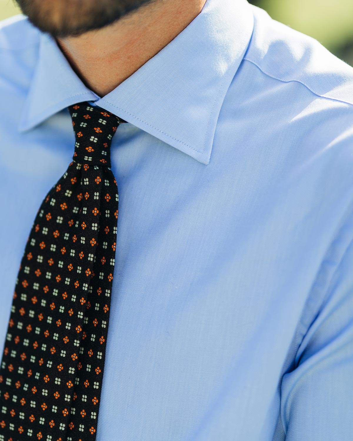 Close-up of a person wearing a light blue shirt and a patterned tie.