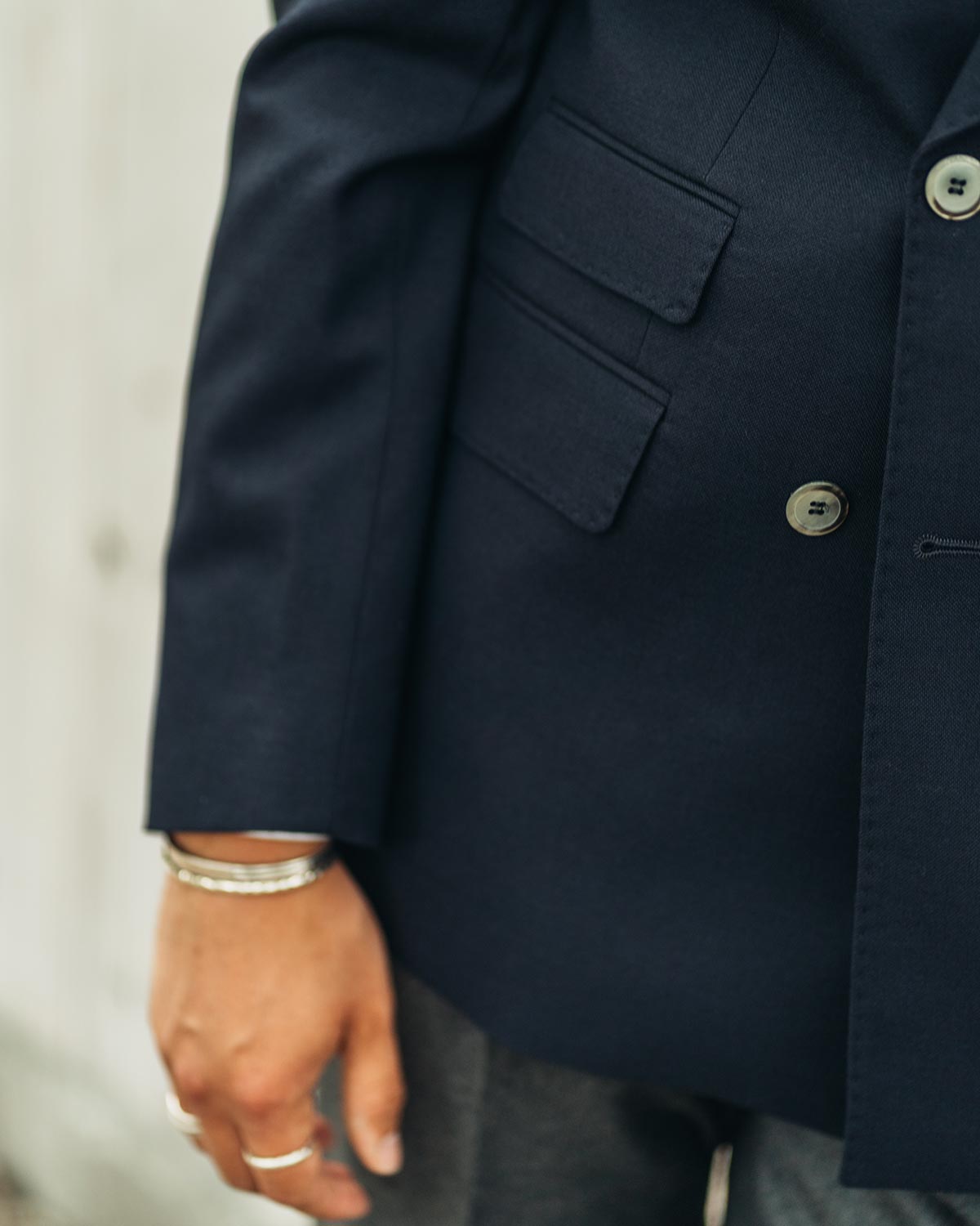 Navy blue jacket close up with two pockets, worn by a person.