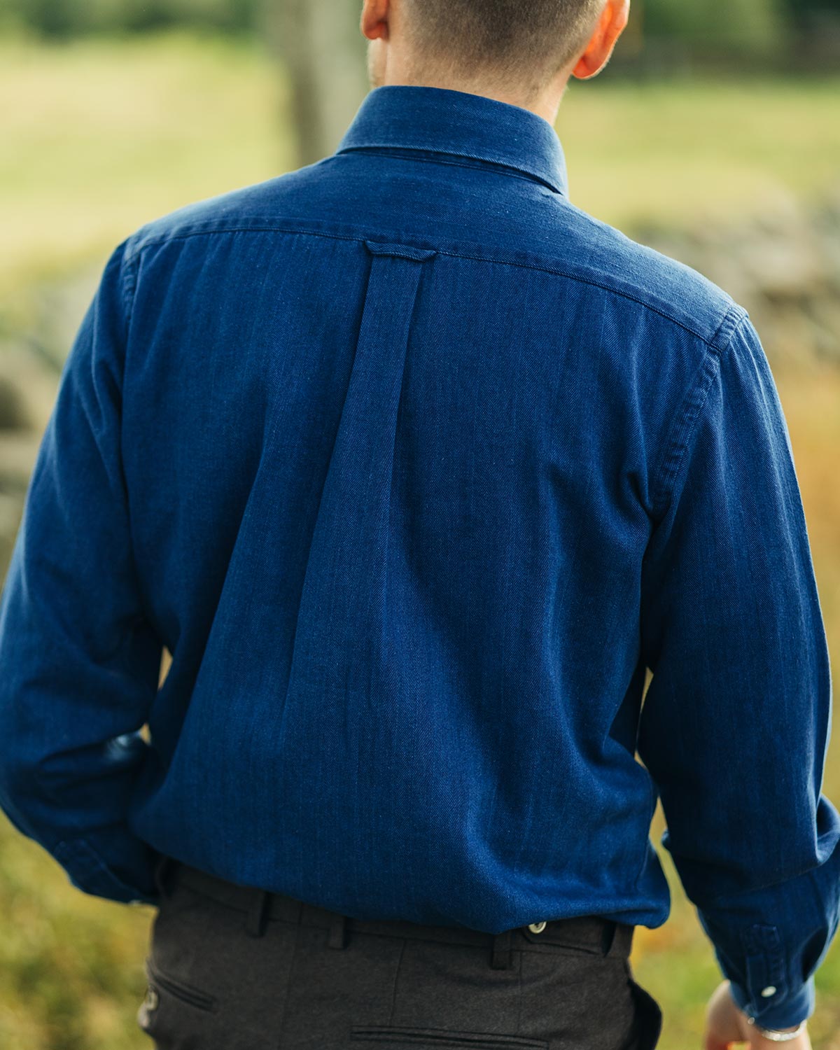 Person wearing a blue denim shirt with a blurred natural background