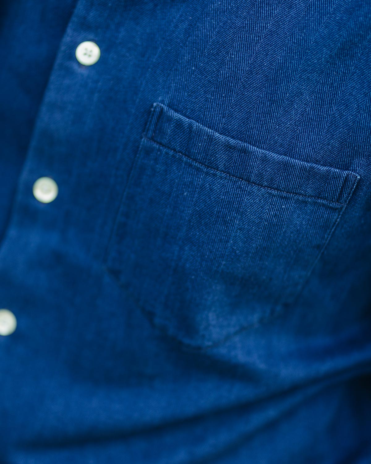 Close-up of a blue denim shirt with buttons and a pocket