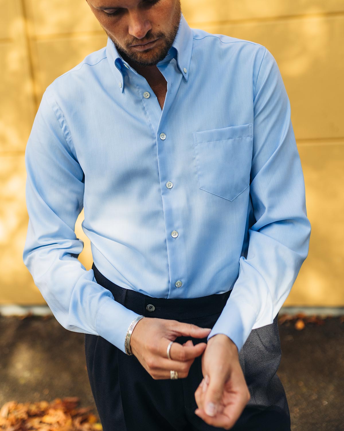 Man wearing a light blue dress shirt against a blurred natural background