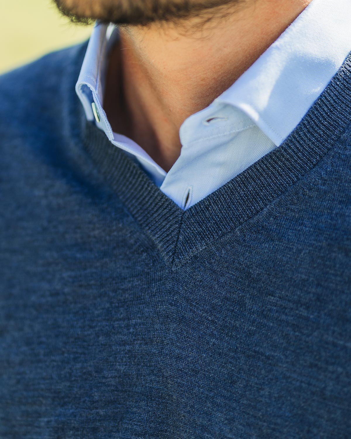 Close-up of a person wearing a blue sweater over a light blue shirt.