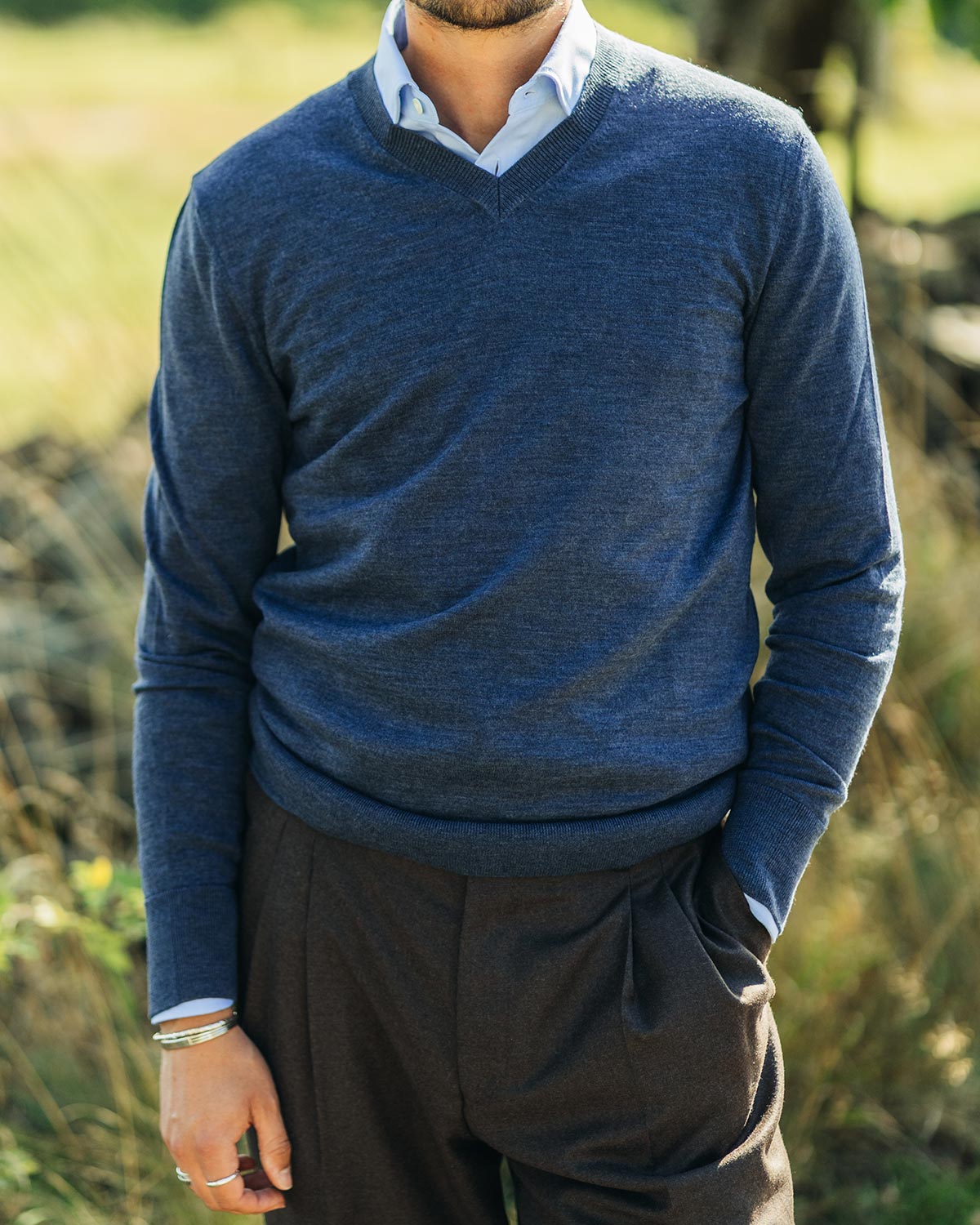 Person wearing a blue sweater and dark pants in a natural setting