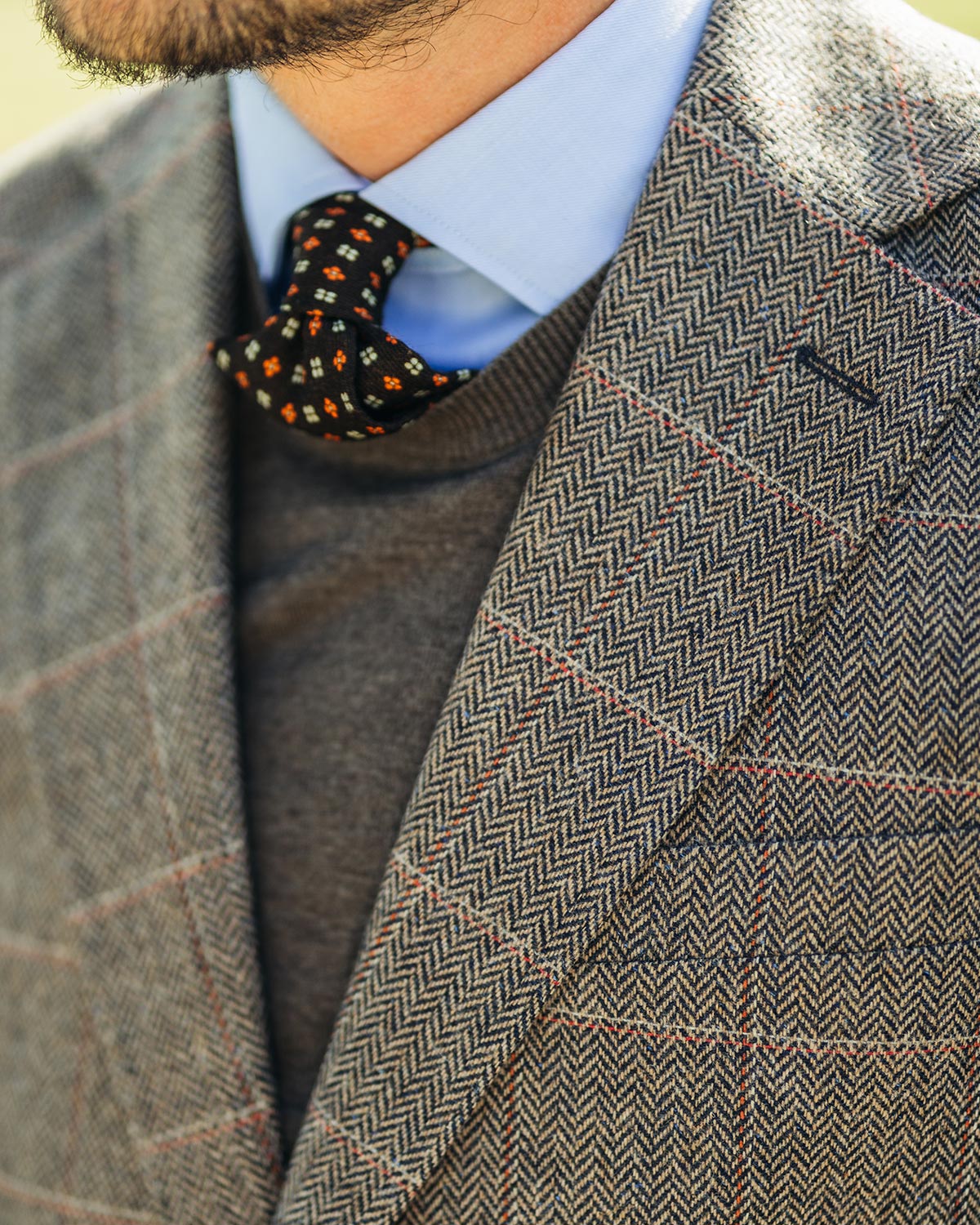 Close-up of a person wearing a patterned tie with a brown checked jacket.
