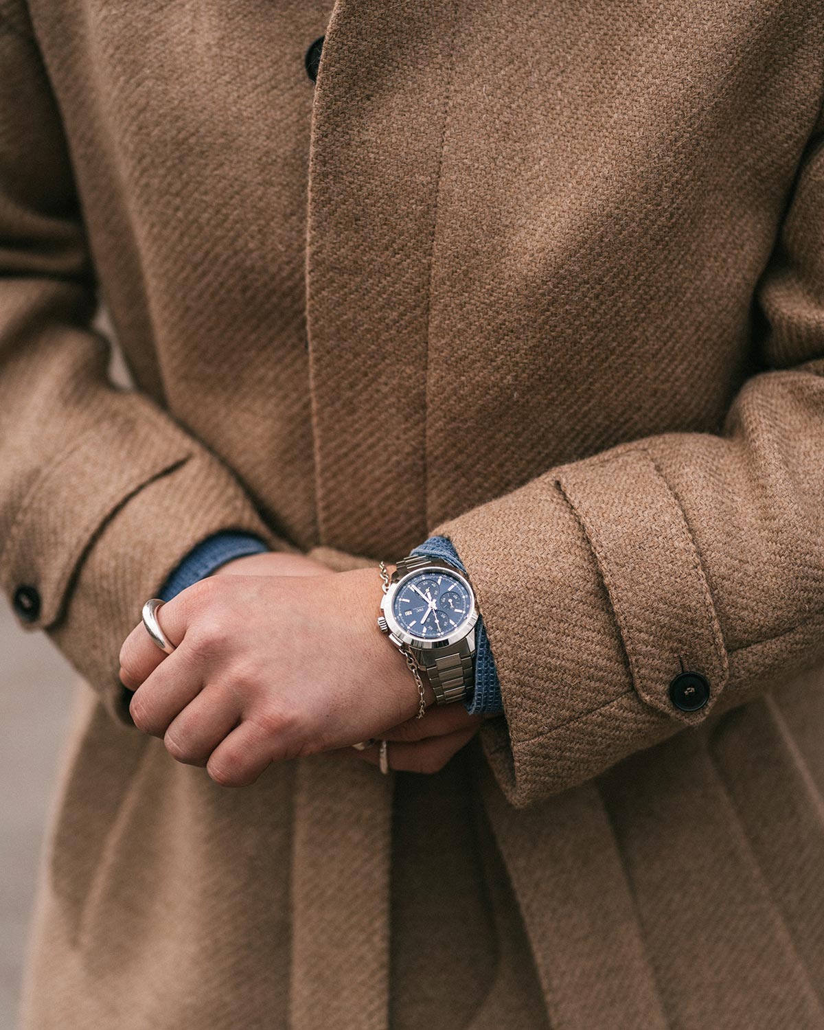 Person wearing a brown coat with a watch on their wrist