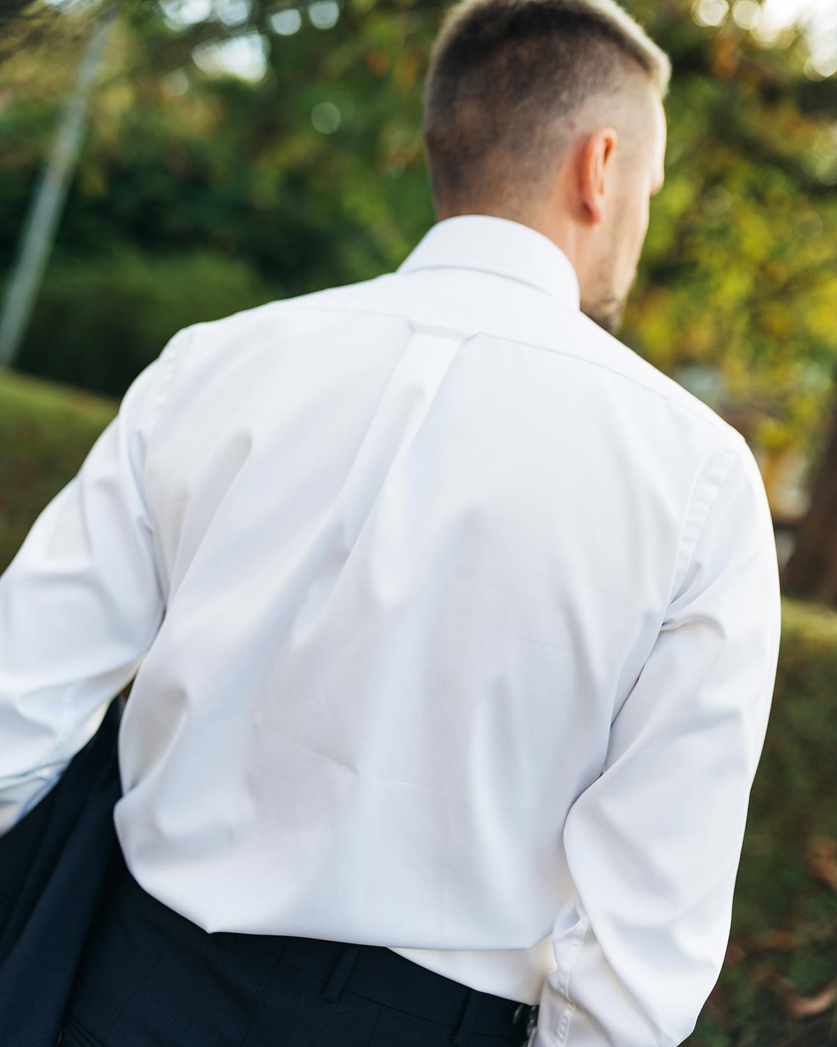Man wearing a white dress shirt with a blurred natural background